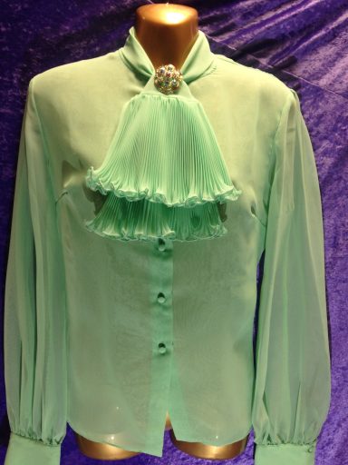 A mint green blouse with long sleeves and a ruffled neck detail.