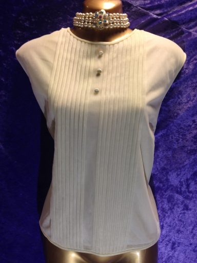 White pleated blouse with short sleeves and three buttons at the front.