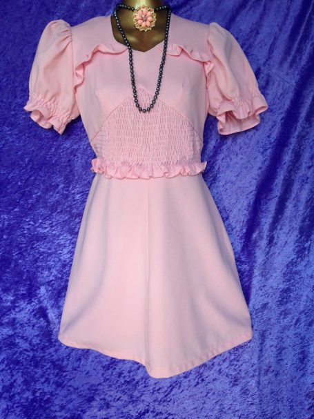 Pink dress with puff sleeves and a ruffled waist, displayed on a mannequin.